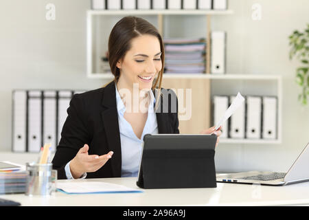 Happy office worker having a video call on tablet at workplace Stock Photo