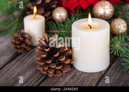 Closeup of a burning candle and holiday decor on a rustic wooden surface Stock Photo