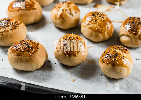 Homemade Turkish Pastries Pogaca with Black Cumin and Sesame Seeds on Baking Paper Sheet with Tray. Traditional Organic Food. Stock Photo