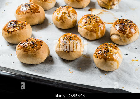 Homemade Turkish Pastries Pogaca with Black Cumin and Sesame Seeds on Baking Paper Sheet with Tray. Traditional Organic Food. Stock Photo