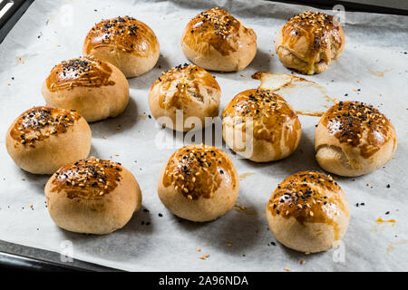 Homemade Turkish Pastries Pogaca with Black Cumin and Sesame Seeds on Baking Paper Sheet with Tray. Traditional Organic Food. Stock Photo