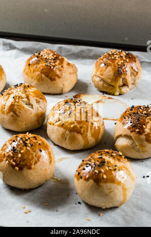 Homemade Turkish Pastries Pogaca with Black Cumin and Sesame Seeds on Baking Paper Sheet with Tray. Traditional Organic Food. Stock Photo