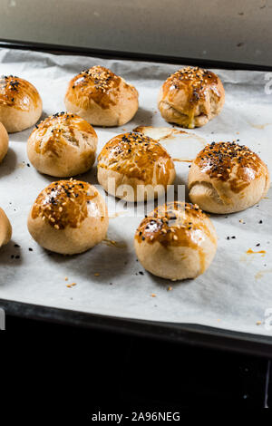 Homemade Turkish Pastries Pogaca with Black Cumin and Sesame Seeds on Baking Paper Sheet with Tray. Traditional Organic Food. Stock Photo