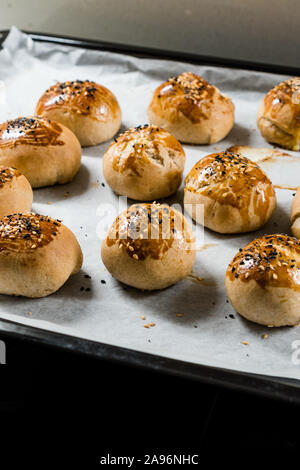 Homemade Turkish Pastries Pogaca with Black Cumin and Sesame Seeds on Baking Paper Sheet with Tray. Traditional Organic Food. Stock Photo
