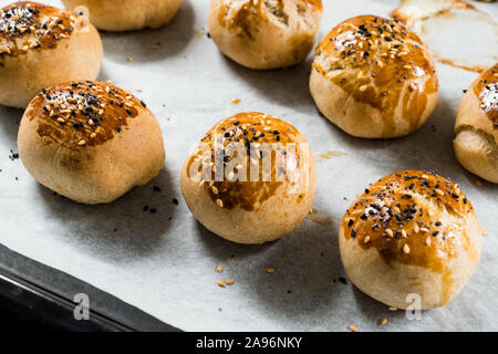 Homemade Turkish Pastries Pogaca with Black Cumin and Sesame Seeds on Baking Paper Sheet with Tray. Traditional Organic Food. Stock Photo