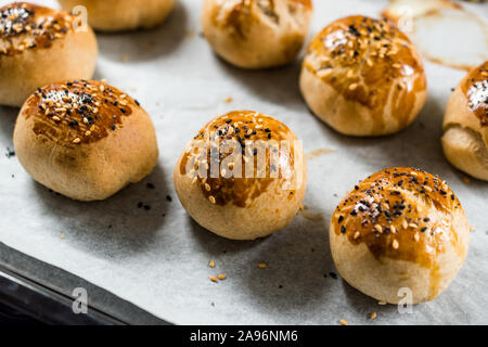 Homemade Turkish Pastries Pogaca with Black Cumin and Sesame Seeds on Baking Paper Sheet with Tray. Traditional Organic Food. Stock Photo