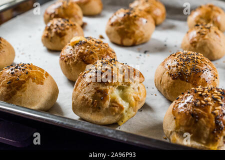Homemade Turkish Pastries Pogaca with Black Cumin and Sesame Seeds on Baking Paper Sheet with Tray. Traditional Organic Food. Stock Photo