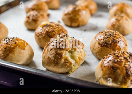 Homemade Turkish Pastries Pogaca with Black Cumin and Sesame Seeds on Baking Paper Sheet with Tray. Traditional Organic Food. Stock Photo