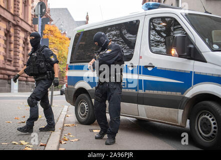 Frankfurt, Germany. 13th Nov 2019. Masked officers of a special police unit secure the evacuation of a suspected terrorist man who had previously been brought before the magistrate at the court centre. The German of Macedonian origin is said to have planned an attack in the Rhine-Main region together with two others. Photo: Boris Roessler/dpa Credit: dpa picture alliance/Alamy Live News Stock Photo