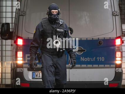 Frankfurt, Germany. 13th Nov 2019. Masked officers of a special police unit secure the evacuation of a suspected terrorist man who had previously been brought before the magistrate at the court centre. The German of Macedonian origin is said to have planned an attack in the Rhine-Main region together with two others. Photo: Boris Roessler/dpa Credit: dpa picture alliance/Alamy Live News Stock Photo