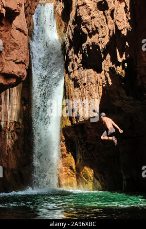 A hiker takes the plunge at Cibeque Falls on Cibeque Creek in Arizona Stock Photo