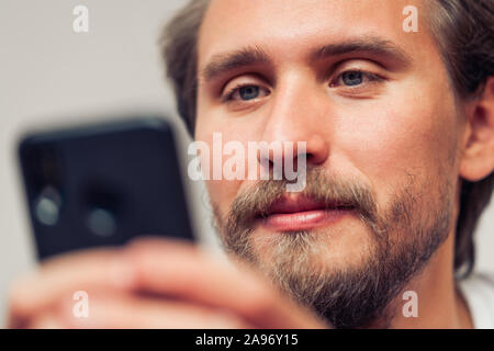 Photo of a handsome young man that is smiling while holding his mobile phone. Stock Photo