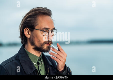 Photo of a young man lighting up a cigarrete Stock Photo