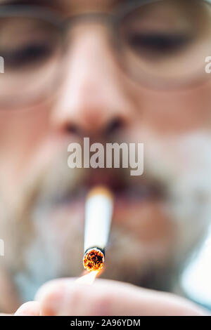 Close-up photo of a young man lighting up a cigarette Stock Photo