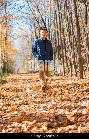 Teenage boy walking alone through the woods on an autumn day. Stock Photo