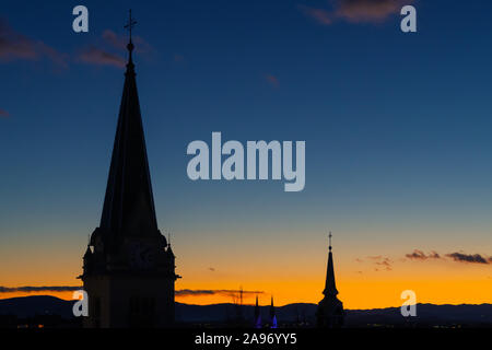 Cityscape silhouette of catholic church towers in Ljubljana on a wonderful orange blue evening sky background. Cityscapes and religion concepts. Stock Photo