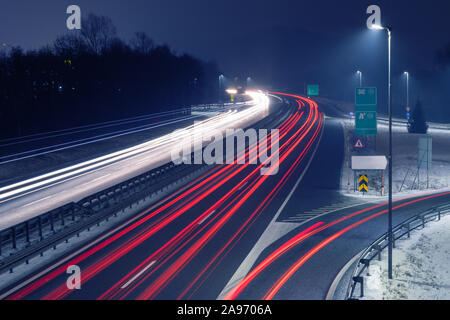 Highway at night with bright trails of light from incoming and outgoing traffic. Transportation, traffic, urbanism and infrastructure concepts. Stock Photo