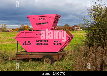 Pink rubbish skips on display in the corner of a field, to advertise a ...