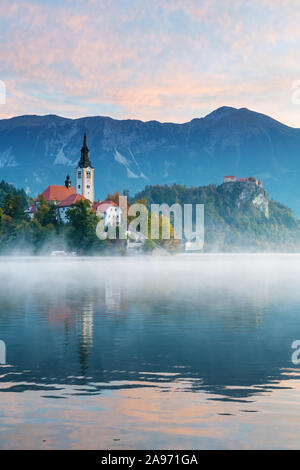 Beautiful morning view of lake Bled with beautiful sky during sunrise in autumn. Old catholic church on island and old castle in Slovenia Stock Photo