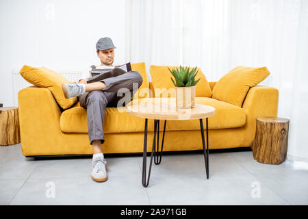 Handyman in workwear sitting on the yellow couch while resting after the work Stock Photo