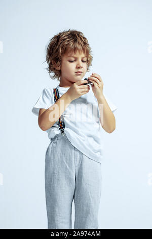 Pretty young boy in casual clothes on white studio background. Fashionable posing, looks confident. Caucasian male preschooler with bright facial emotions. Childhood, expression, having fun. Stock Photo
