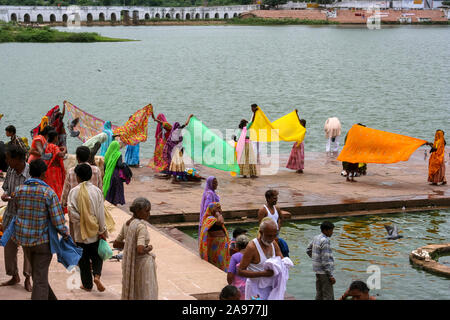 Pushkar, Rajasthan, India: Indian women blow wet saris on the shores (ghat) of the holy Pushkar lake Stock Photo