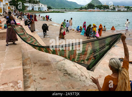 Pushkar, Rajasthan, India: two Indian women blow wet saris on the shores (ghat) of the holy Pushkar lake Stock Photo