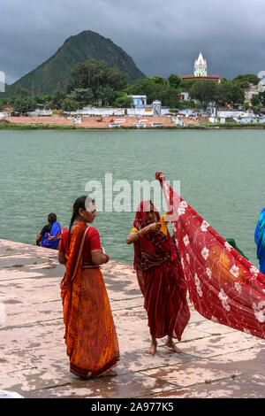 Pushkar, Rajasthan, India: two Indian women blow wet saris on the shores (ghat) of the holy Pushkar lake Stock Photo