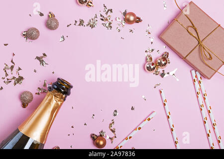 Creative composition with golden colored decor, sparkles asn campagne bottle on pink background. Stock Photo