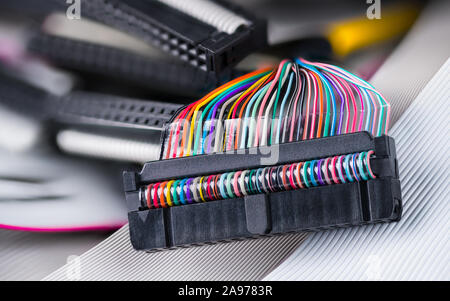 Colored multi wire connector. Ribbon cables detail in blurred background. Internal drive electronics for data storage devices as floppy or hard disks. Stock Photo