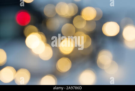Blurred gold and red Christmas decorative lights glittering on blue foggy background with festive mood. Abstract glowing Xmas and New Year decorations. Stock Photo