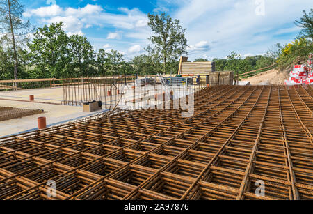 Reinforcing bars grid for ferroconcrete. Building foundations in green trees. Rebar mesh of rust brown steel wires for reinforced concrete and masonry. Stock Photo