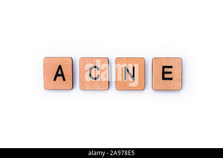 The word ACNE, spelt with wooden letter tiles over a white 