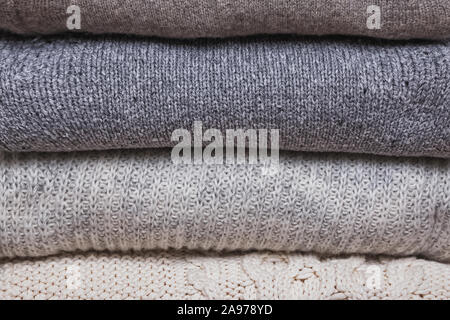 Bunch of knitted warm sweaters, different knitting patterns folded in stack Stock Photo