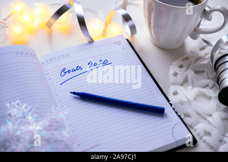 2020 goals written on a diary with light, hot coffe or tea and decoration. Happy New Year and motivation consept background Stock Photo