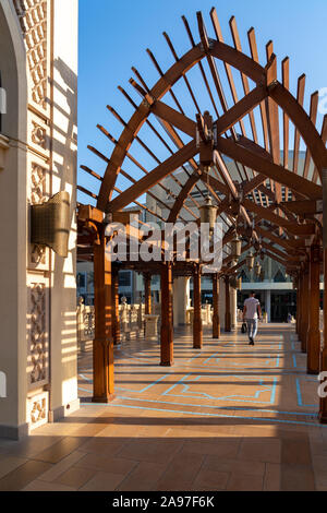 Man walking under wood arches along a bridge to Dubai Mall in Dubai, United Arab Emirates. Stock Photo