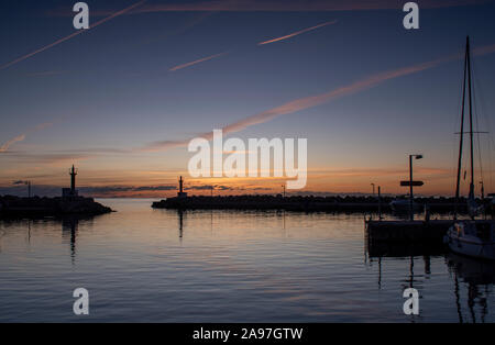 Cala Bona Marina Majorca Sunrise an array of golden colours and dramatic sky reflecting in the calm harbour water. Stock Photo