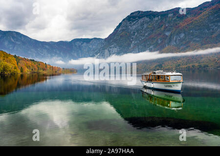 A tour boat  on a calm Lake Bohinj with fall foliage color, Slovenia, Europe. Stock Photo