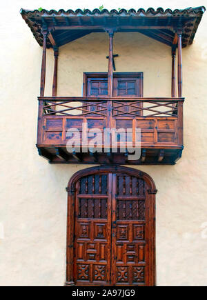 Wood canary balcony over a wood door in a yellow wall Stock Photo