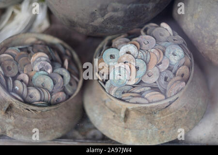 Old Chinese coins with a square hole in metal vessels in an antique shop. Vietnam. Stock Photo