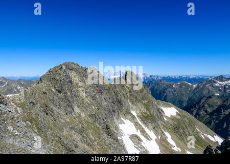 Massive, sharp stony mountain range of Schladming Alps, Austria. The mountain has a pyramid shape, it is partially overgrown with green bushes. Danger Stock Photo