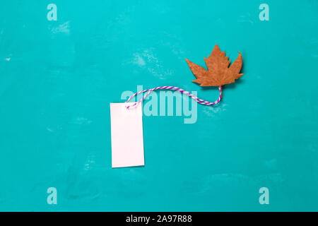 top view mock up blank white paper label and maple leaf on a turquoise background Stock Photo