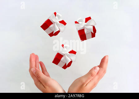 red gift boxes with white festive  bows fly into female hands Stock Photo