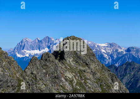 Massive, sharp stony mountain range of Schladming Alps, Austria. The mountain has a pyramid shape, it is partially overgrown with green bushes. Danger Stock Photo