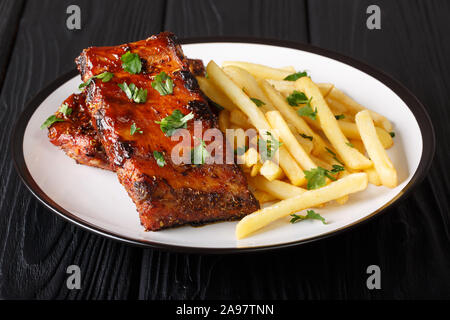 Barbecue recipe from grilled ribs with french fries close-up on a plate on the table. horizontal Stock Photo