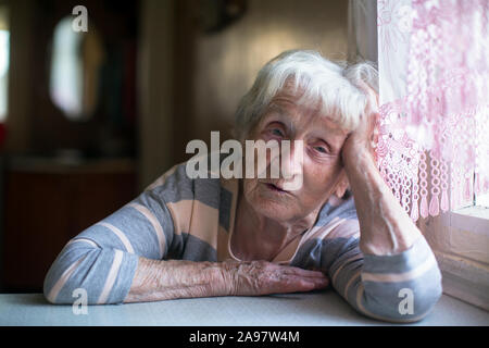 Portrait of a pensioner woman at the table in home. Stock Photo