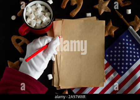 pattern of ginger cookies shaped like stars and letters merry Christmas and sheets of vintage blank paper with space for text and Santa Claus hand in Stock Photo