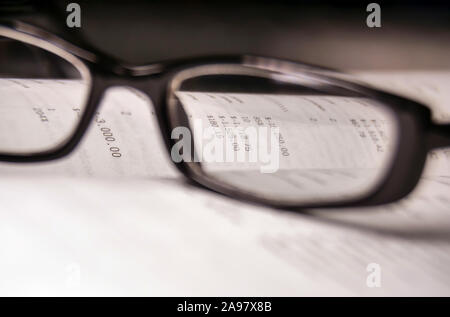 Figures from the financial report through the glass of glasses in a black frame Stock Photo