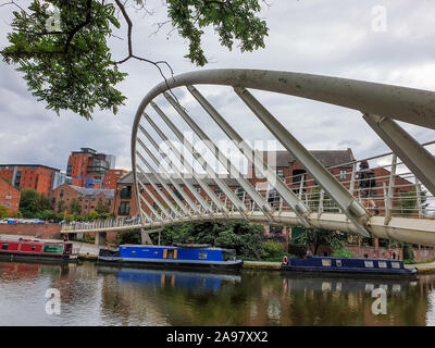 Manchester, United Kingdom - July 26, 2019: A pedestrian crosses a pedestrian bridge in the rennovated Castlefield district in Manchester, UK Stock Photo