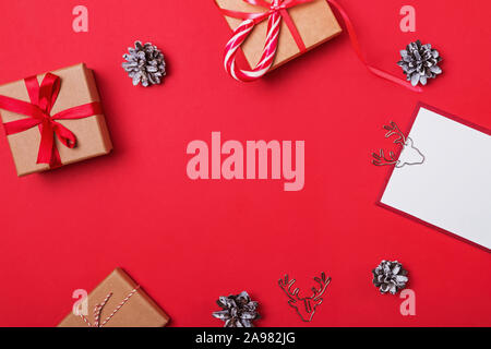 Christmas frame with gift boxes and pine cones on red background Stock Photo
